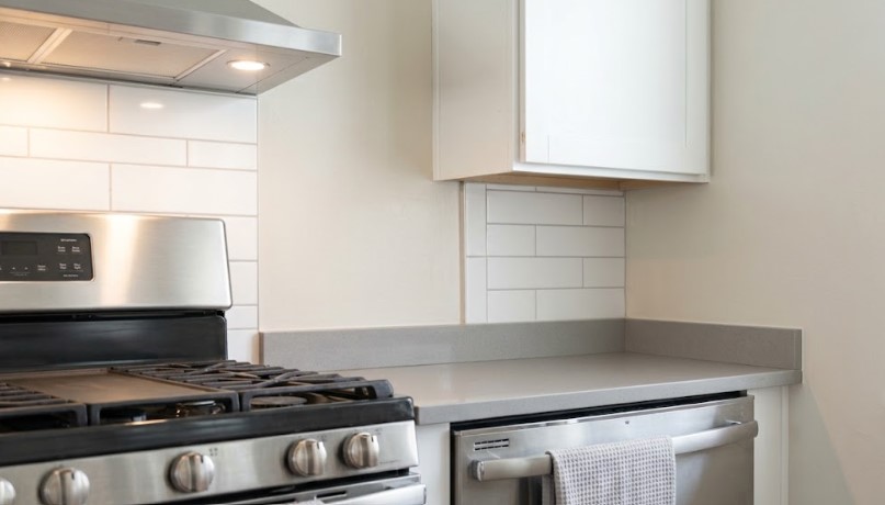 Freshly painted kitchen wall beside a stainless range hood and white tile backsplash