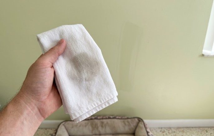 Damp white cloth showing dirt wiped from a painted wall